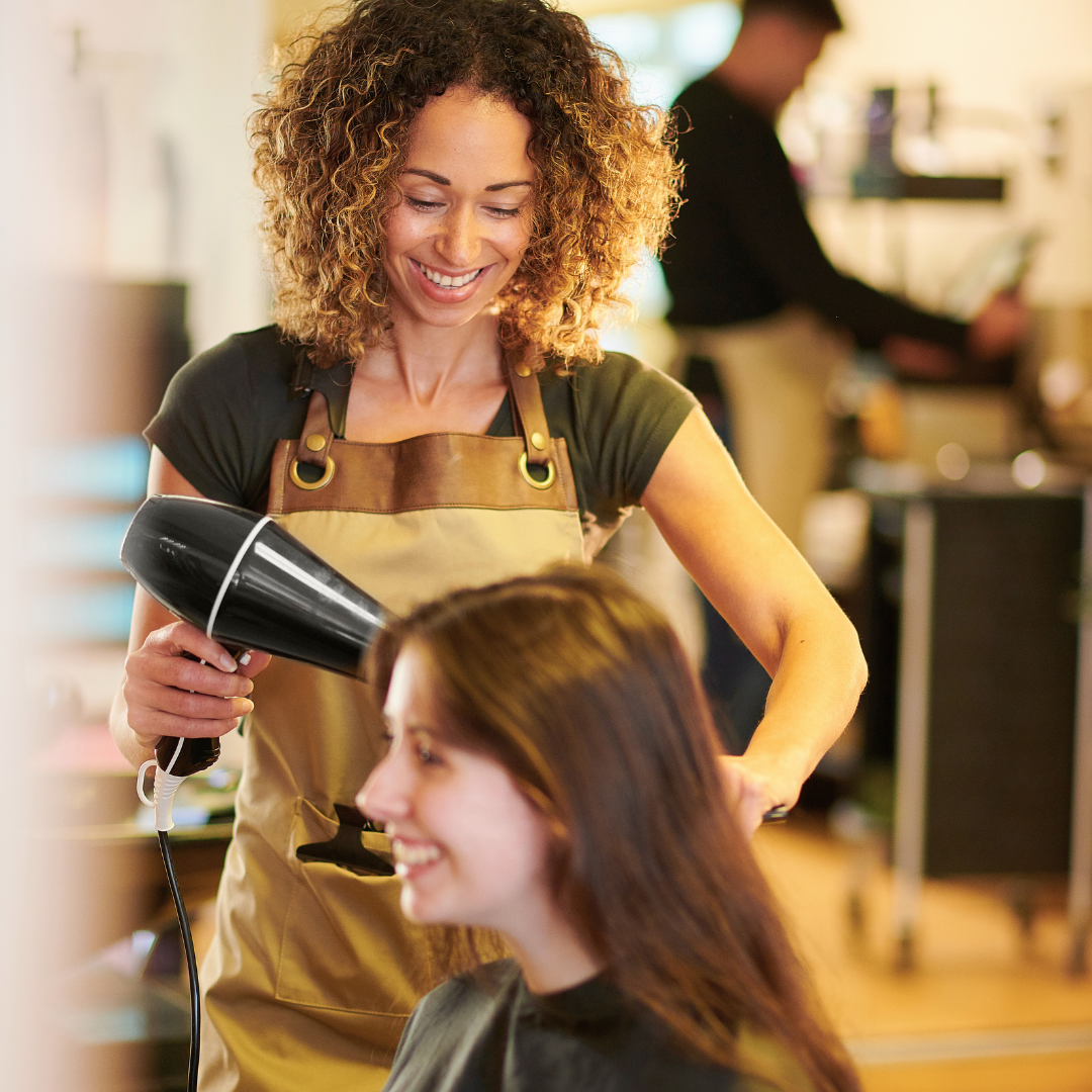 Beauty professional styling a client’s hair during an appointment in a salon.